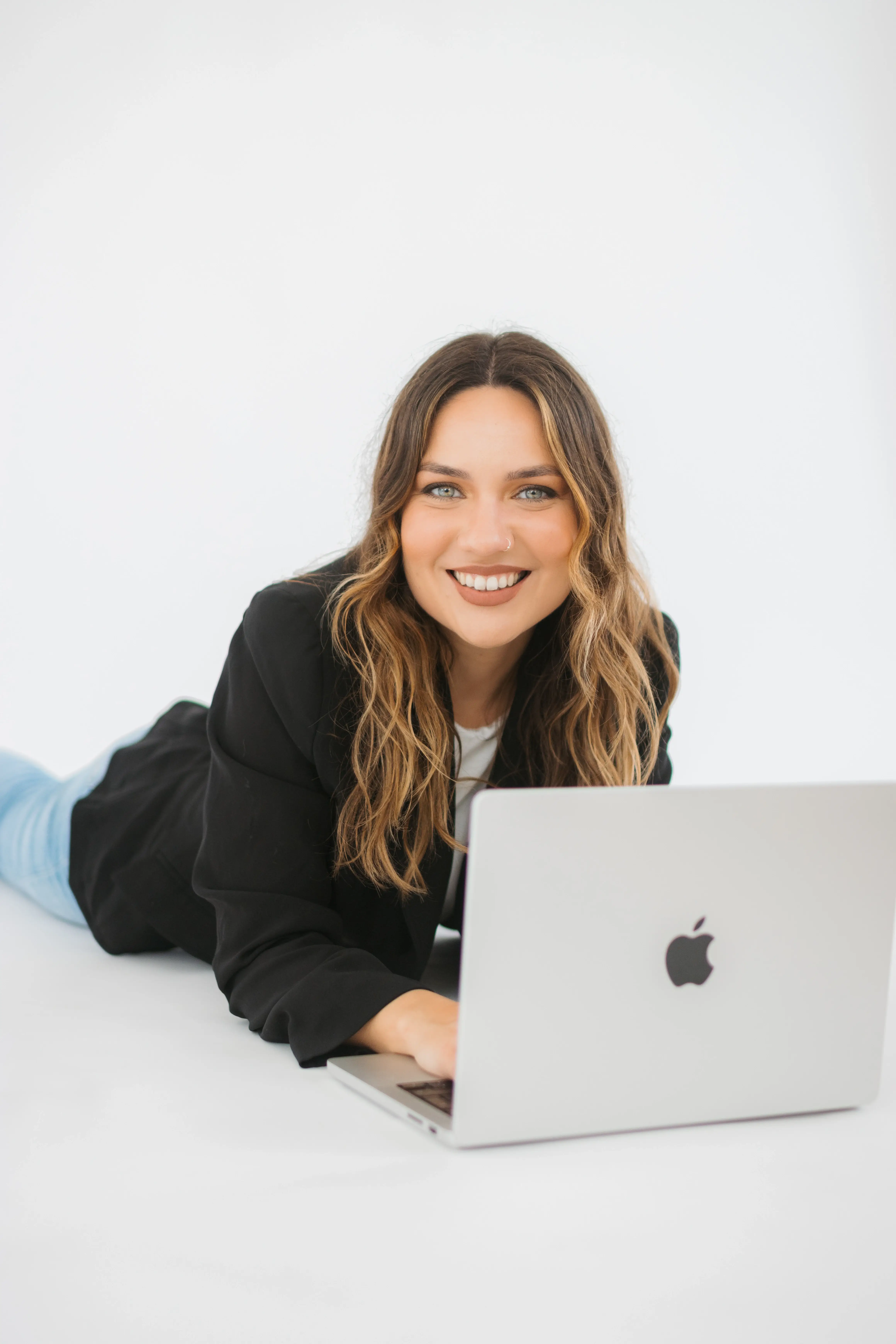soraia, hipnoterapeuta deitada no chão ao computador a olhar e a sorrir com confiança para a camara